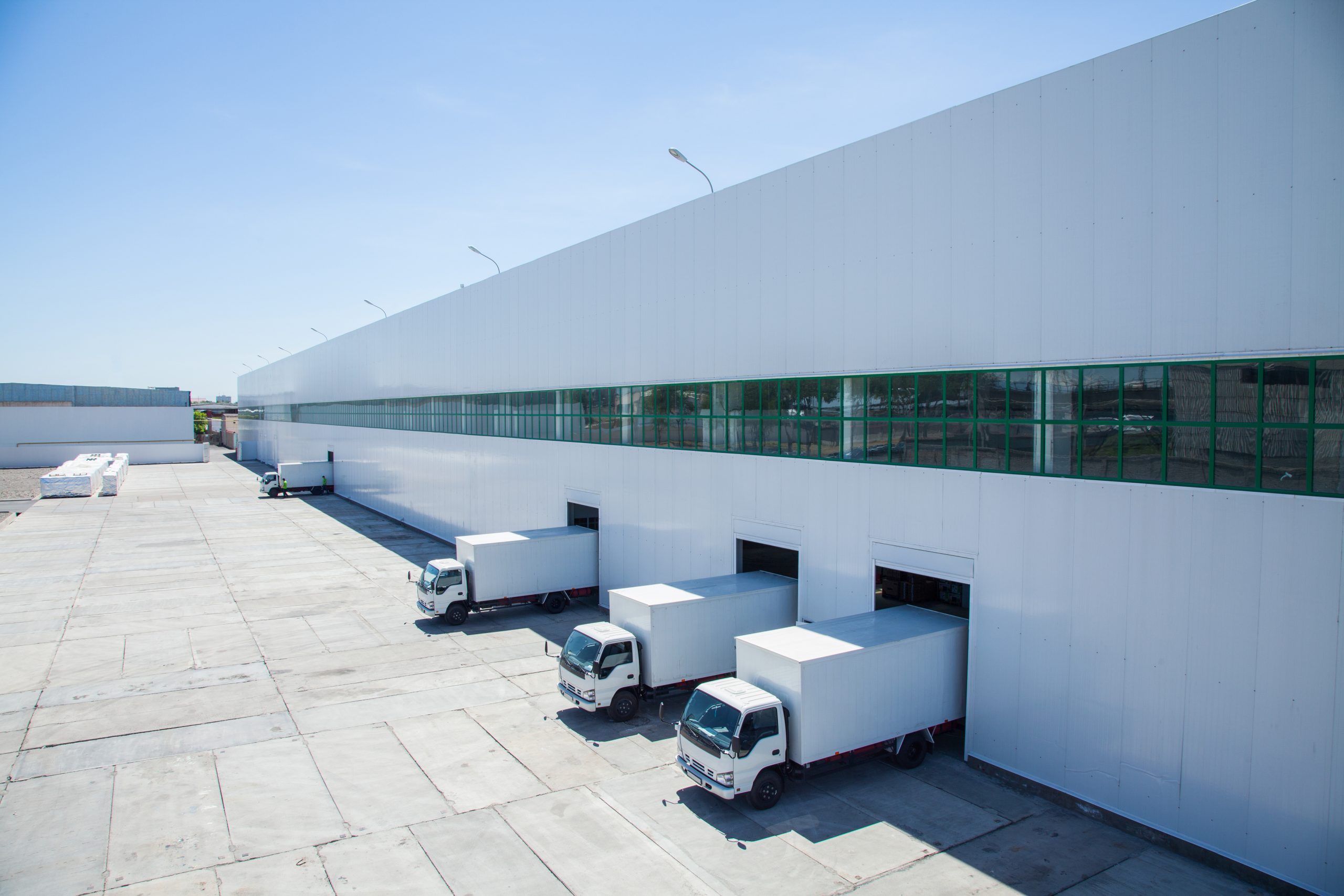 Trucks parked at a warehouse loading dock under a clear blue sky.